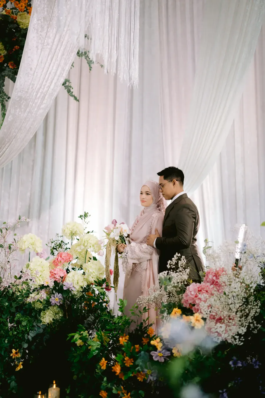 Bride and groom surrounded by pastel wedding flowers