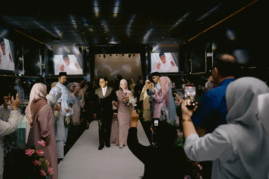 Bride and groom entering their wedding celebration surrounded by guests