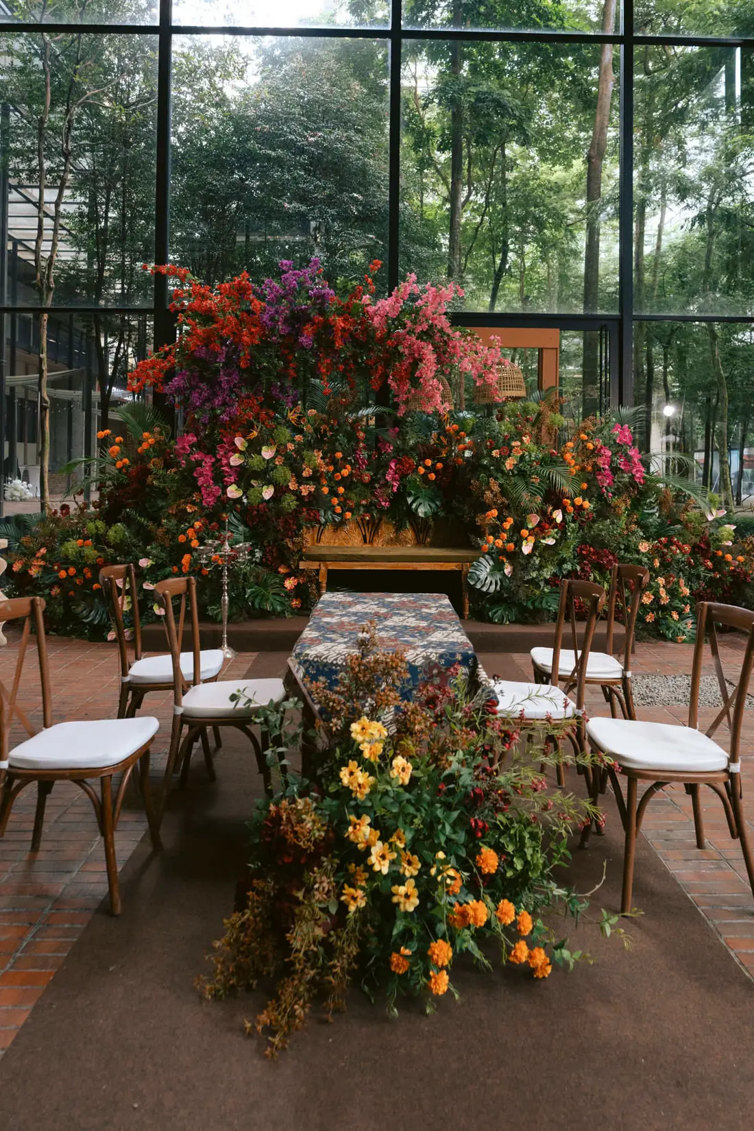 A floral arch styled for a ceremony inside the Luminare Sanctuary glass box, with the garden behind