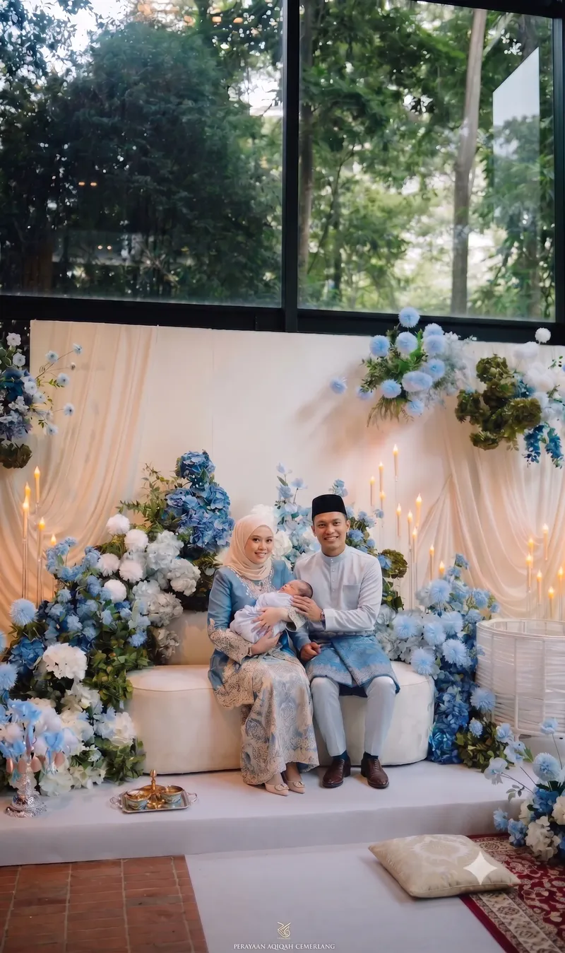 A family celebrating an aqiqah in front of blue floral styling
